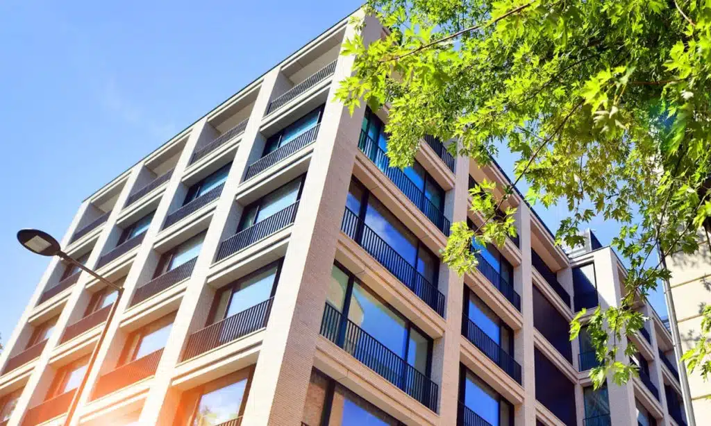 Un immeuble moderne sous un grand ciel bleu derrière un arbre bien vert