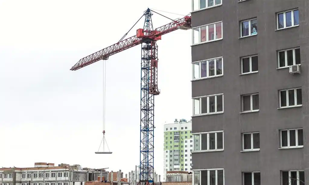 Une grue qui déplace une charge sur le chantier de construction d'un immeuble.