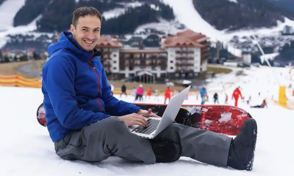 Un investisseur immobilier avec son ordinateur sur une piste dans une station de ski
