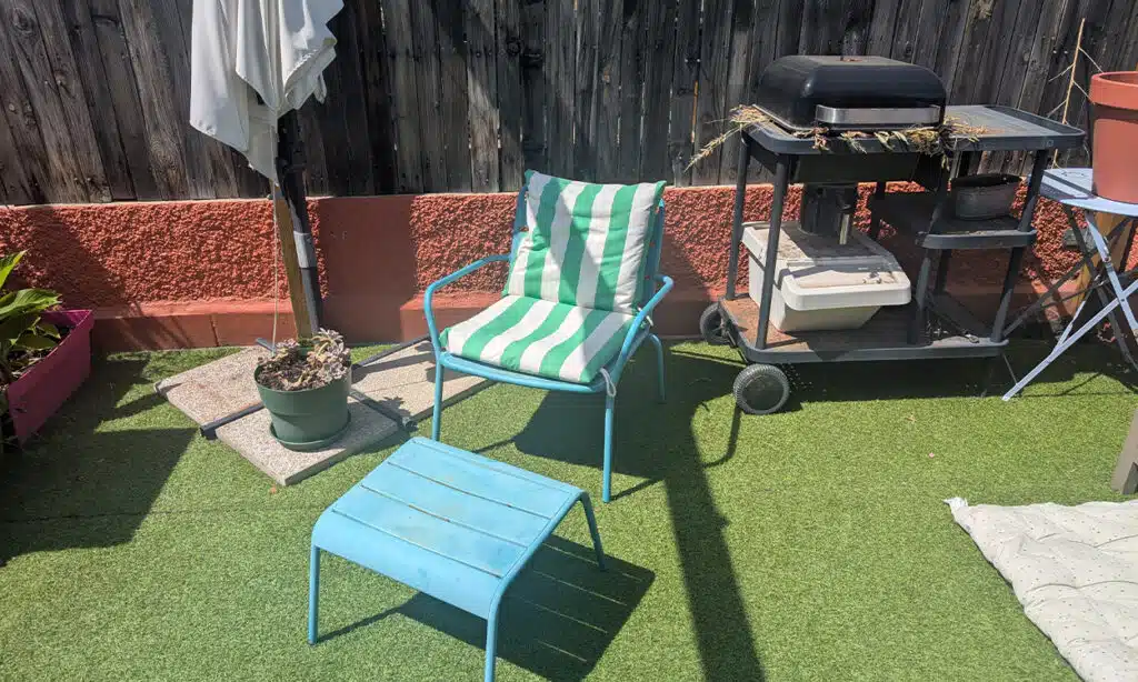Photo d'un gazon synthétique sur un toit terrasse décoré avec un fauteuil de jardin et un barbecue