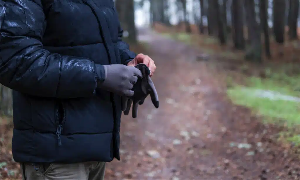 Un homme anonyme avec des gants noirs en forêt