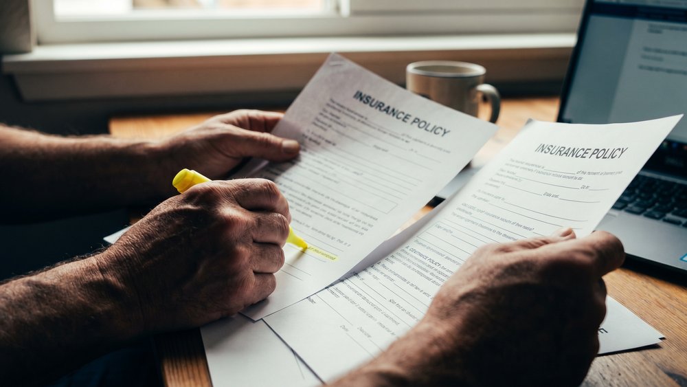 Mains comparant deux offres d'assurance emprunteur au surligneur
