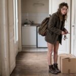 Une jeune etudiante s'installe dans un petit studio, cles a la main et carton