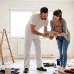 Un artisan et une proprietaire verifient ensemble un devis de travaux de renovation dans un logement