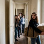 Une jeune femme visite un studio pendant qu'une file de candidats attend, illustrant la tension locative et l'encadrement des loyers