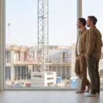 Un couple visite un appartement neuf avec vue sur un chantier de construction et une grue