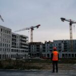 Chantier de construction de logements neufs en France avec grues, un ouvrier observe le ralentissement de la promotion immobiliere