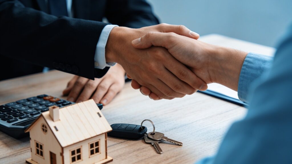 Mains d un conseiller et d un client autour d une calculatrice et de cles de maison