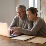 Un couple de proprietaires cree son compte France Renov sur un ordinateur portable dans un logement en travaux