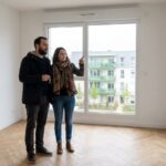 Un couple visite un appartement neuf vide d'une residence collective, cles en main, avant sa mise en location